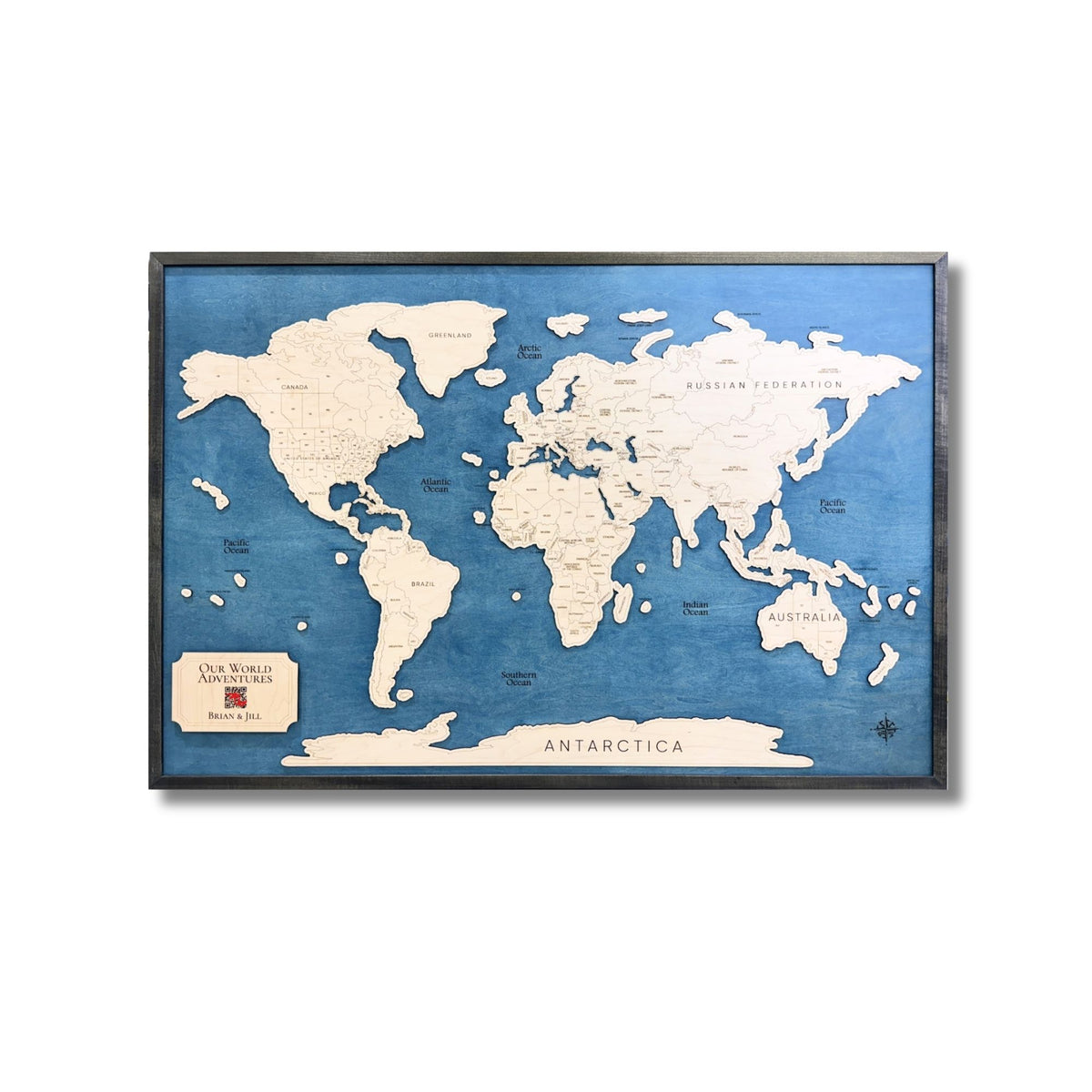 Wooden world travel map with black frame on a white background.