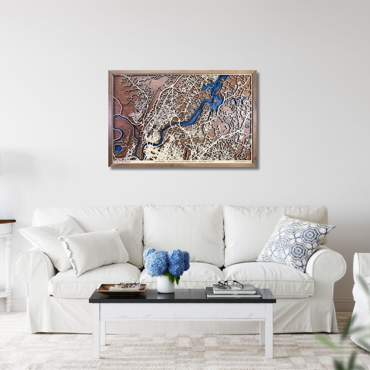 Framed wooden city map of Chattanooga, TN hanging on a living room wall above a sofa.