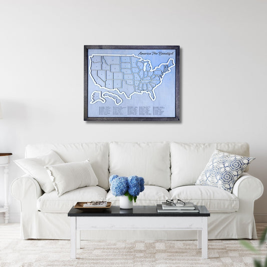 Wooden United States Travel Map hanging on a wall in a living room above a sofa and coffee table. 
