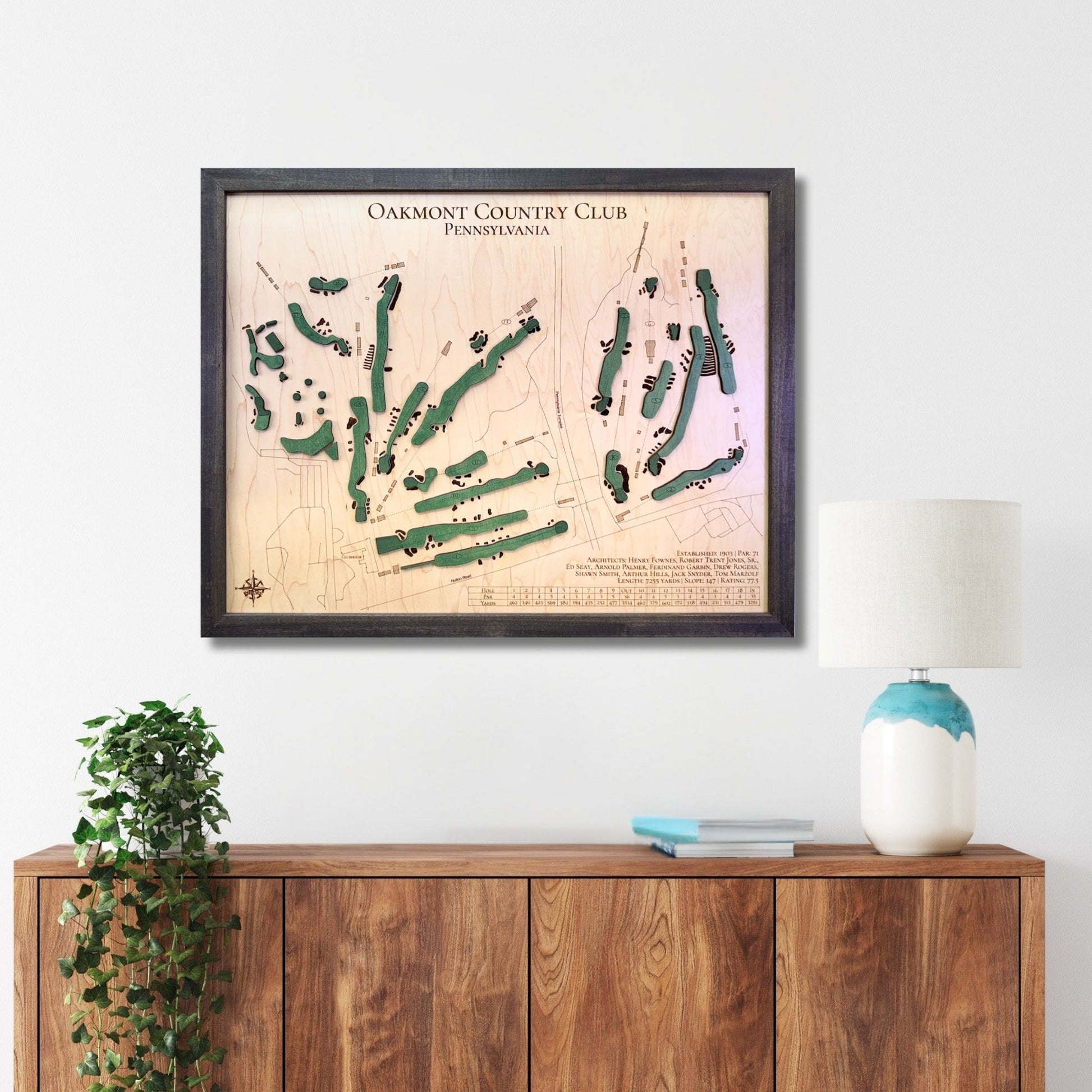 Framed Oakmont golf map hanging on a wall above a wooden console. 