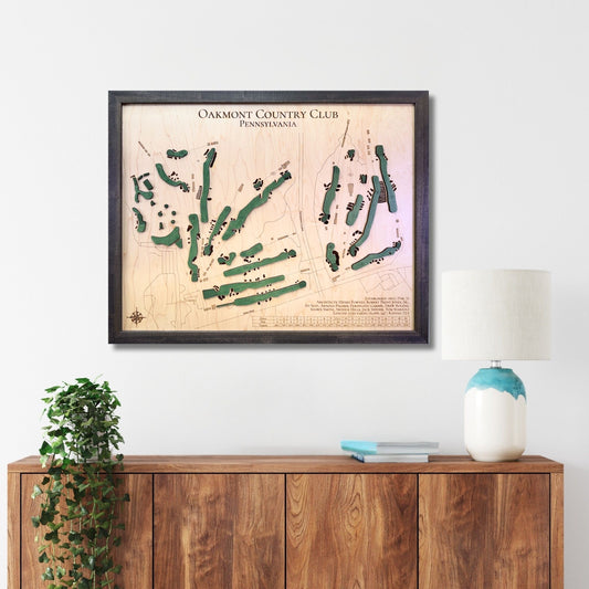 Framed Oakmont golf map hanging on a wall above a wooden console. 