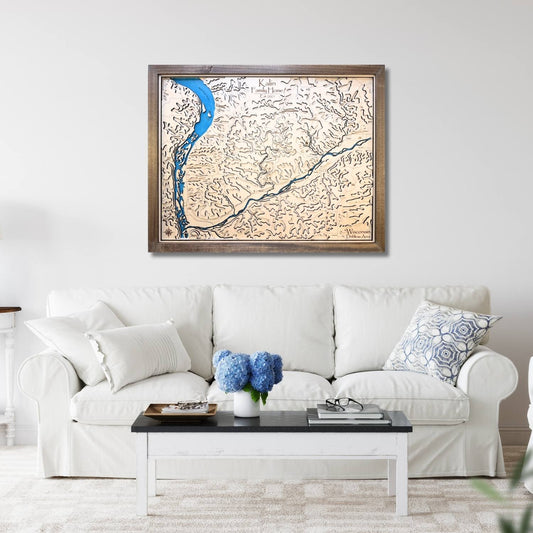 Framed topographic map above a white sofa with decorative pillows and a coffee table.