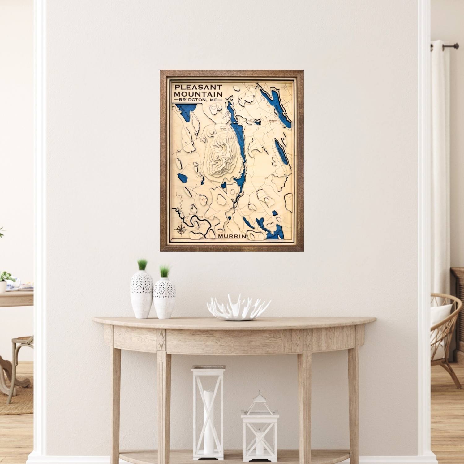 Framed topographic map of Pleasant Mountain on a wall above a wooden table.
