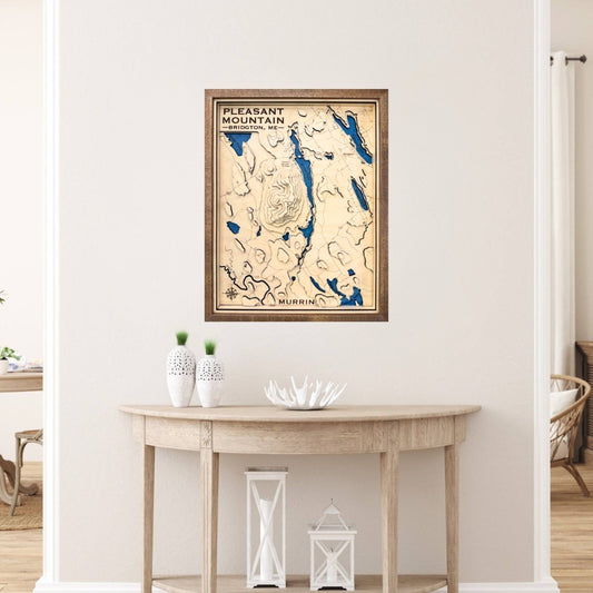 Framed topographic map of Pleasant Mountain on a wall above a wooden table.