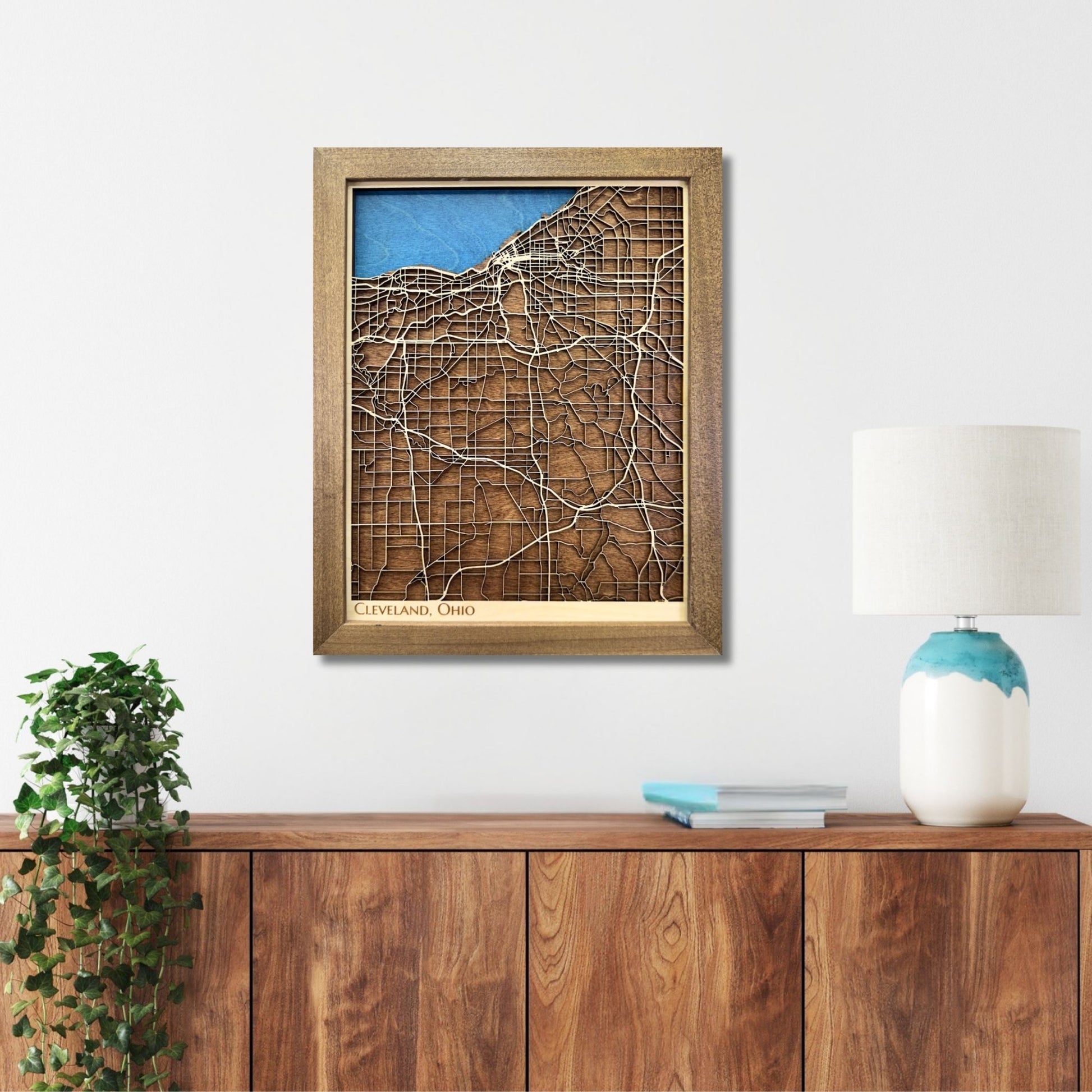 Wooden map of Cleveland, Ohio hanging on a wall above a console. 