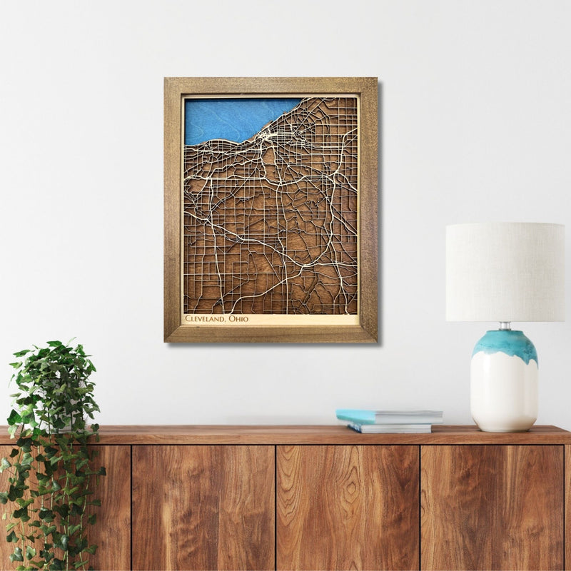 Wooden map of Cleveland, Ohio hanging on a wall above a console. 