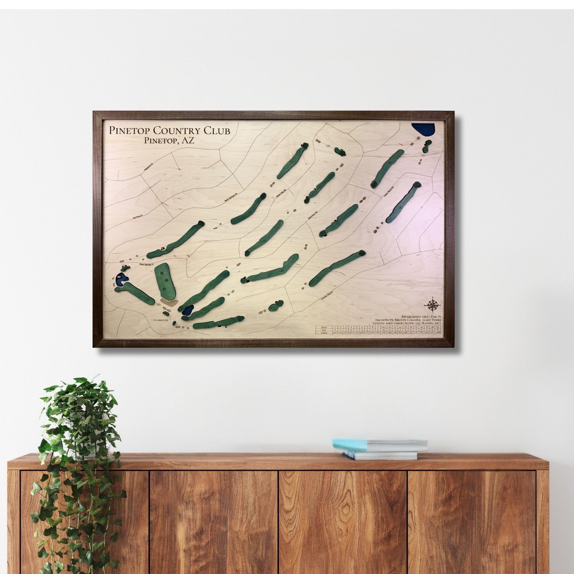 A large golf course map hanging on a wall above a wooden console. 