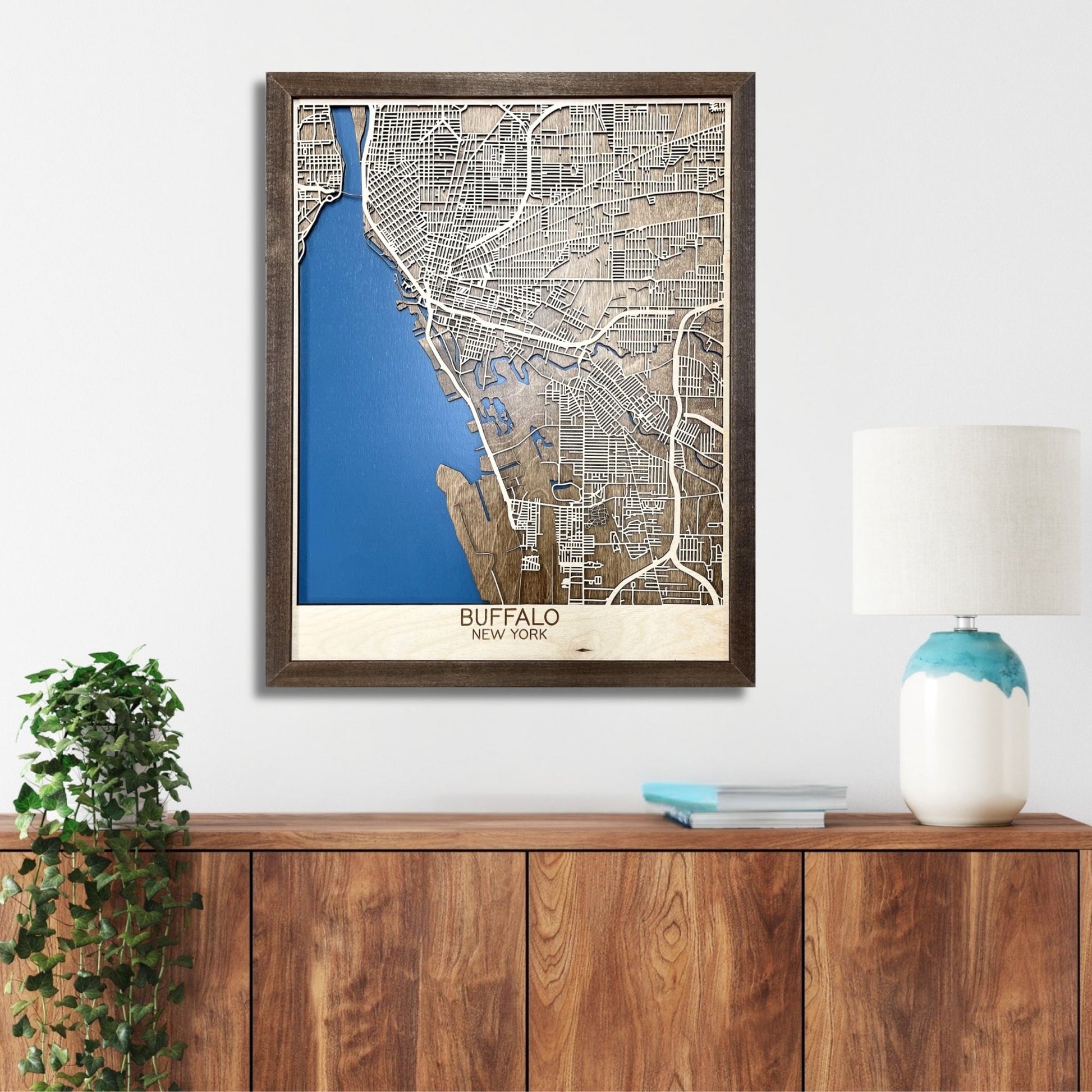 Wooden map of Buffalo, NY hanging on a wall above a console. 