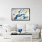 Framed wooden map of Burntside Lake on a wall above a white sofa with decorative pillows.