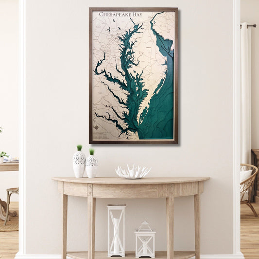 Framed 3D wooden map of Chesapeake Bay on a wall above a wooden console table.