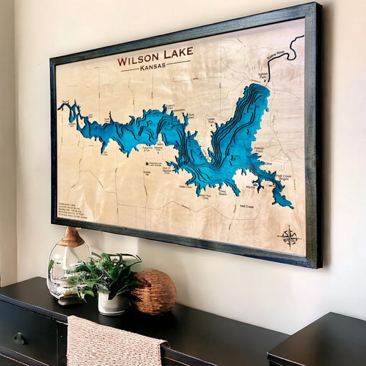 Sideview of a framed wooden map of Wilson Lake hanging on a wall above a dresser. 