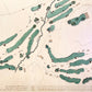 Close up of wooden golf course map with green fairways, blue water hazards, and engraved text. 