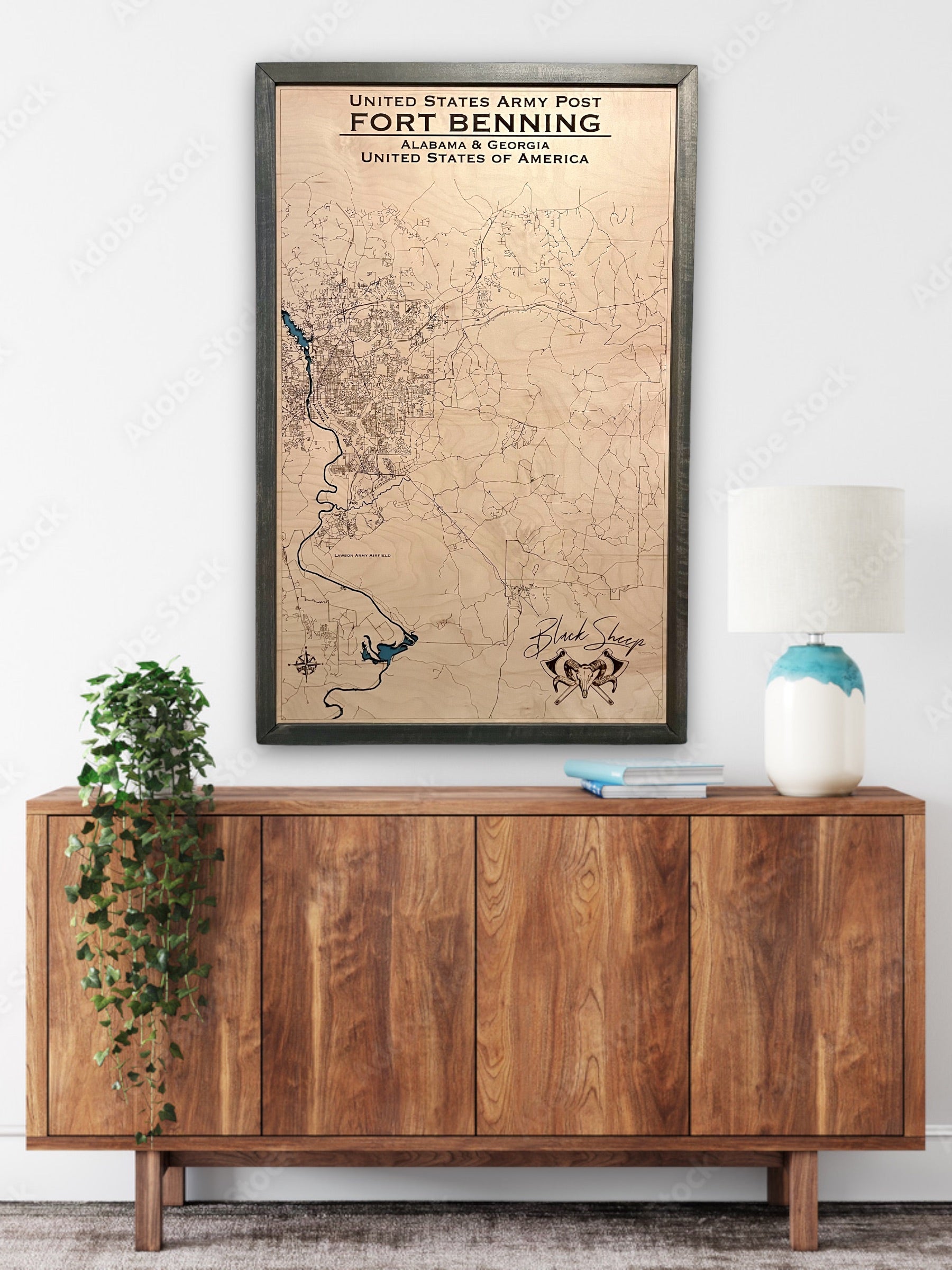 Large custom wooden military map of Fort Benning hanging on wall above a dresser. 