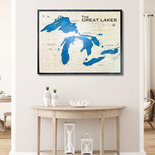 Wooden 3D map of The Great Lakes framed on a wall above a wooden table.