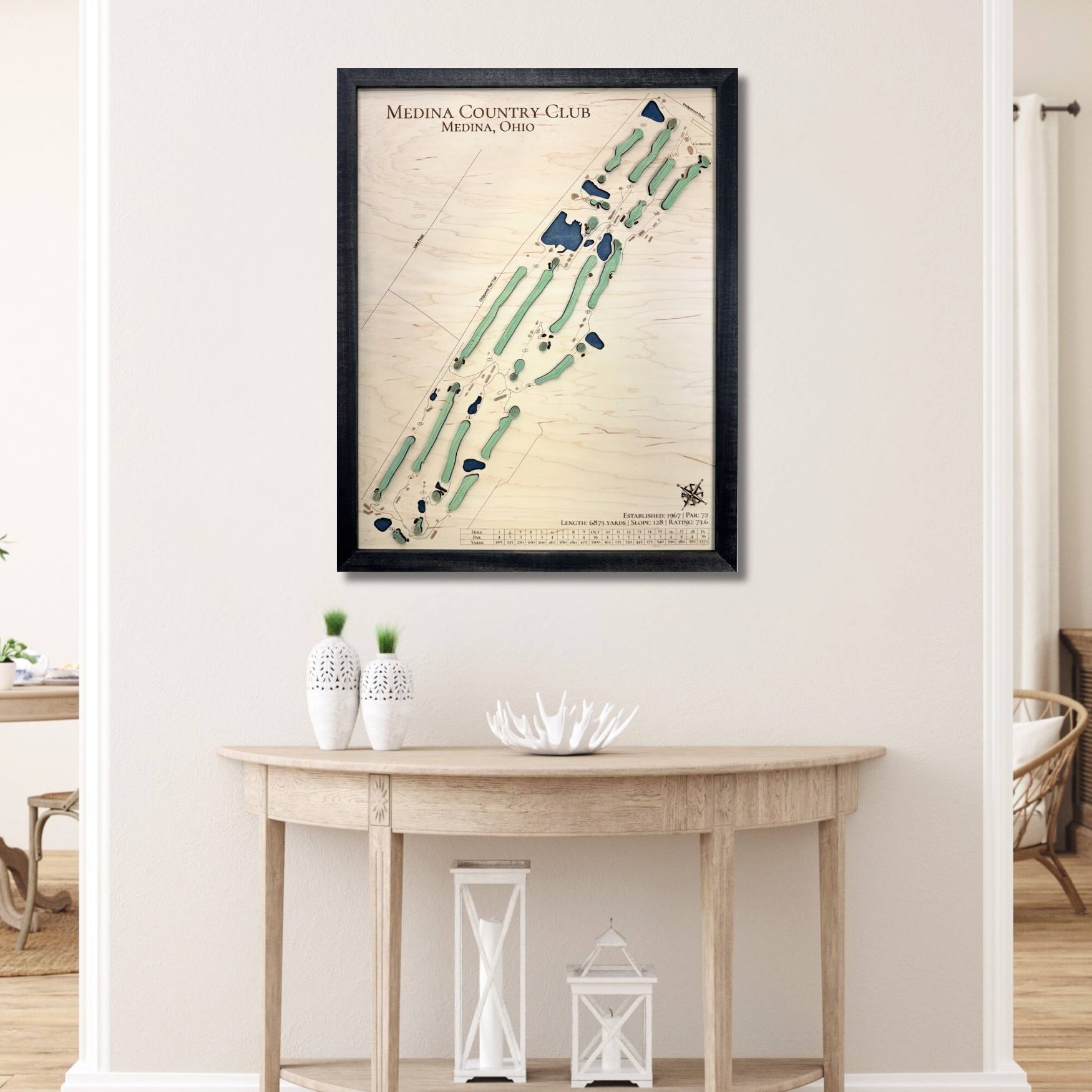 Framed wooden map of Medina Country Club on a wall above a wooden table.