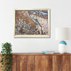 Framed Portland city map on a wall above a wooden cabinet with a plant and lamp.