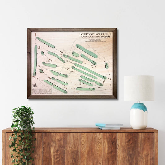 Framed wooden map of a golf course on a wall above a wooden cabinet with decor items.