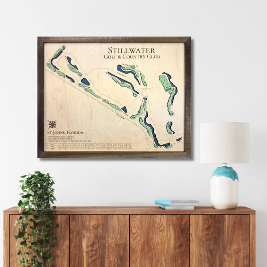 Framed wooden map of Stillwater Golf & Country Club on a wall above a wooden console table.