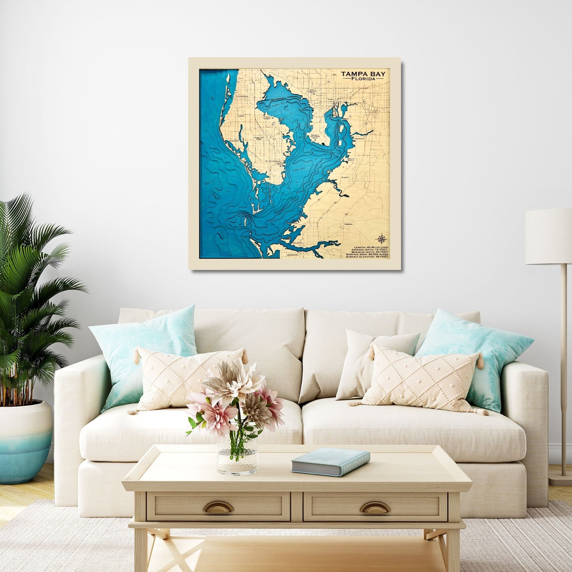 Framed wooden map of Tampa Bay on a wall above a living room sofa with decorative pillows.