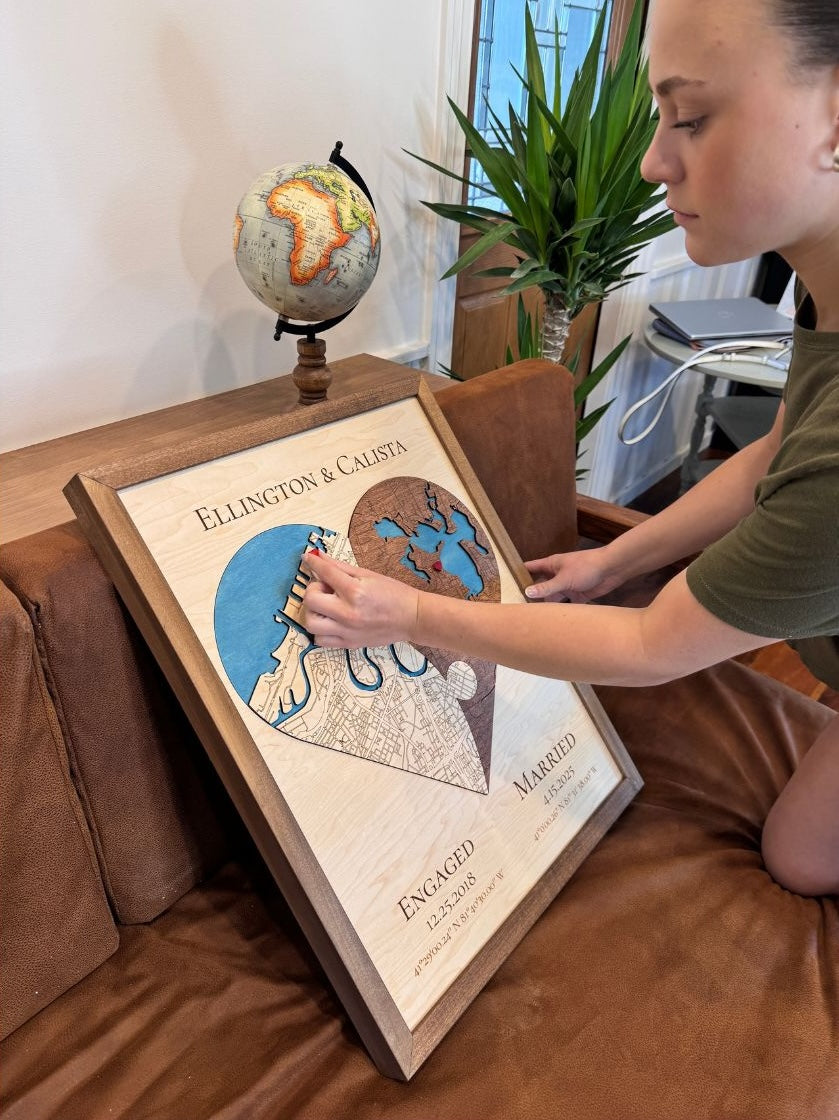 A woman is placing a red heart icon on a two-toned heart-shaped map.