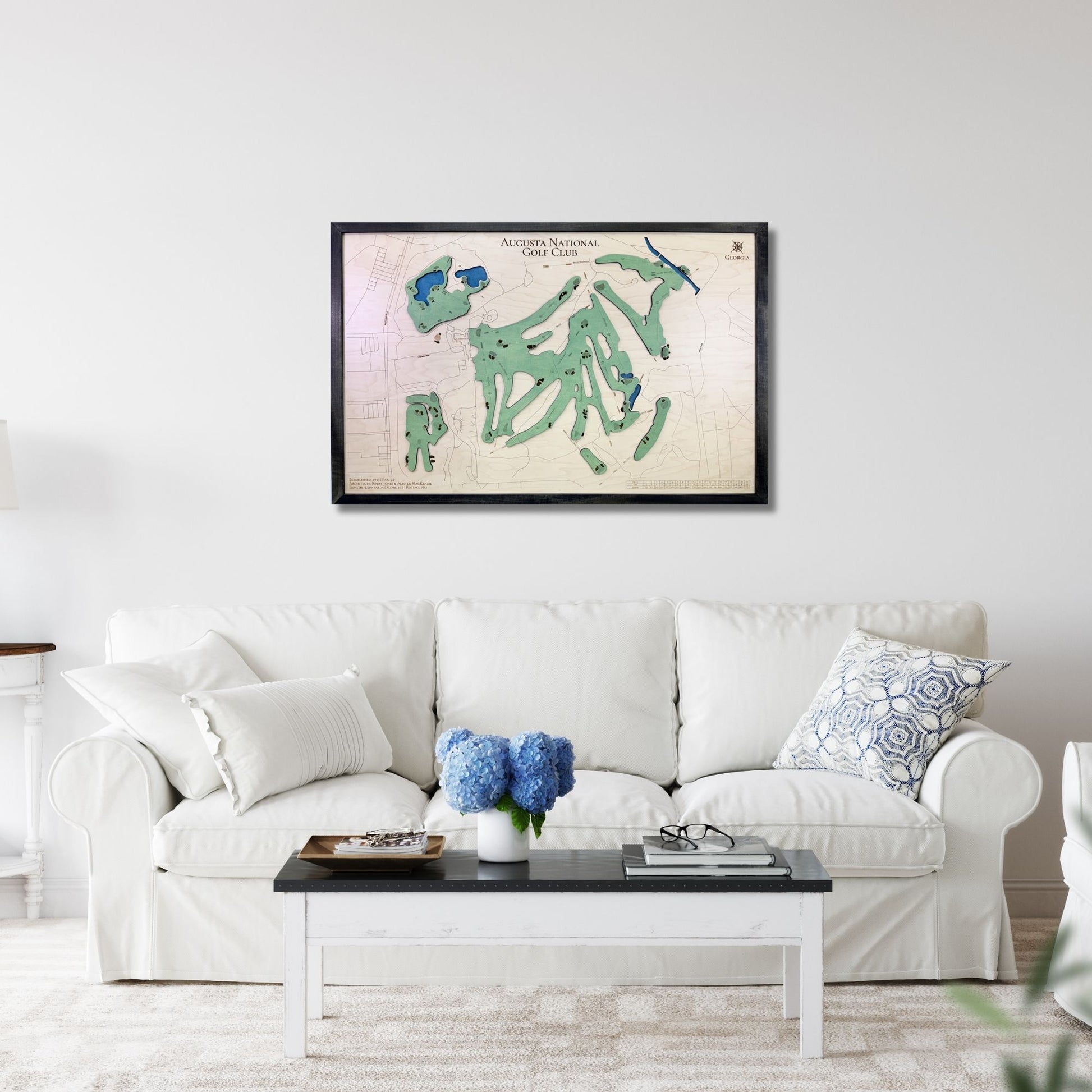 Living room with a white sofa, coffee table, and framed golf map of Augusta National Golf Club hanging on the wall. 