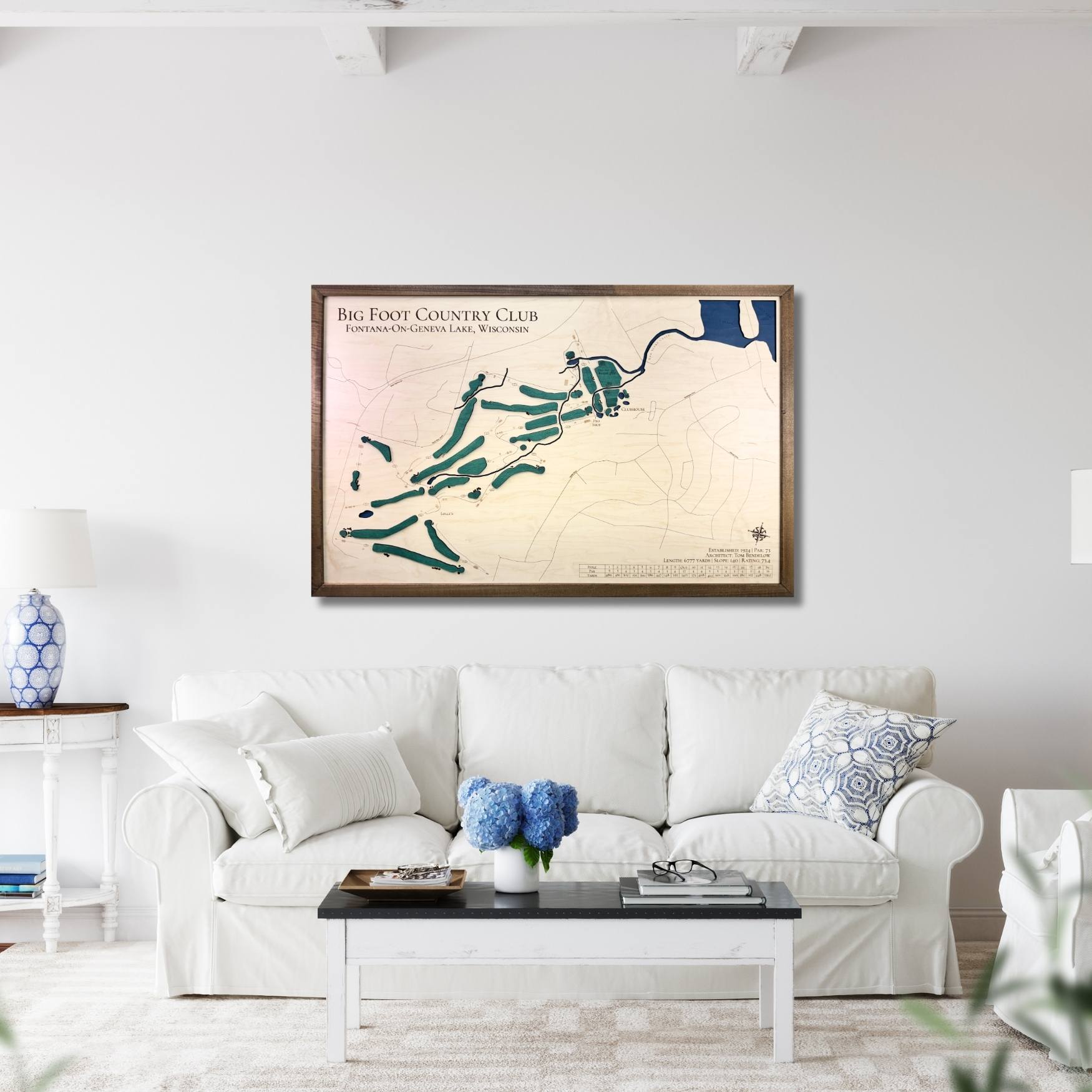 Living room with a framed map of Big Foot Country Club on the wall above a white sofa.