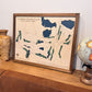 Framed 3D map of Catawba Island Club on a wooden surface with decorative items.