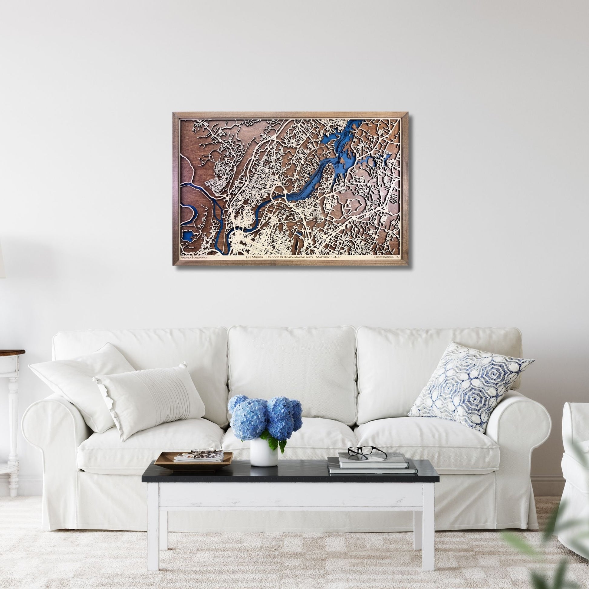 Framed wooden city map of Chattanooga, TN hanging on a living room wall above a sofa. 