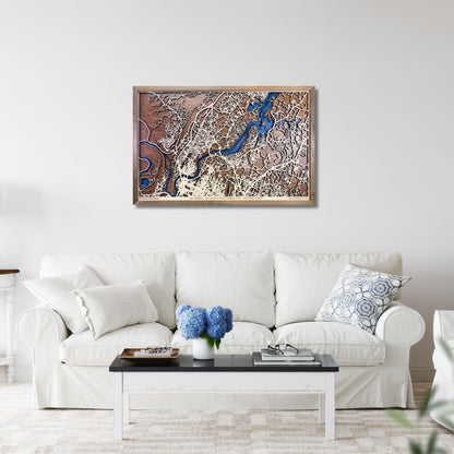Framed wooden city map of Chattanooga, TN hanging on a living room wall above a sofa. 