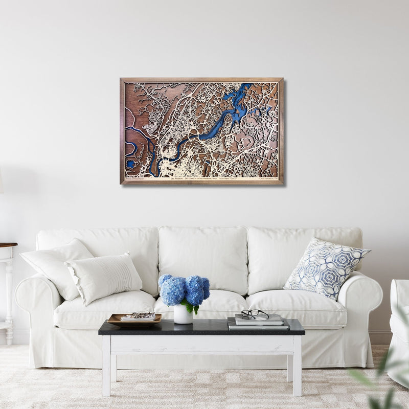 Framed wooden city map of Chattanooga, TN hanging on a living room wall above a sofa. 