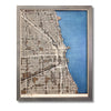 A wooden city map of Chicago with dark blue water stain and beige raised roads.
