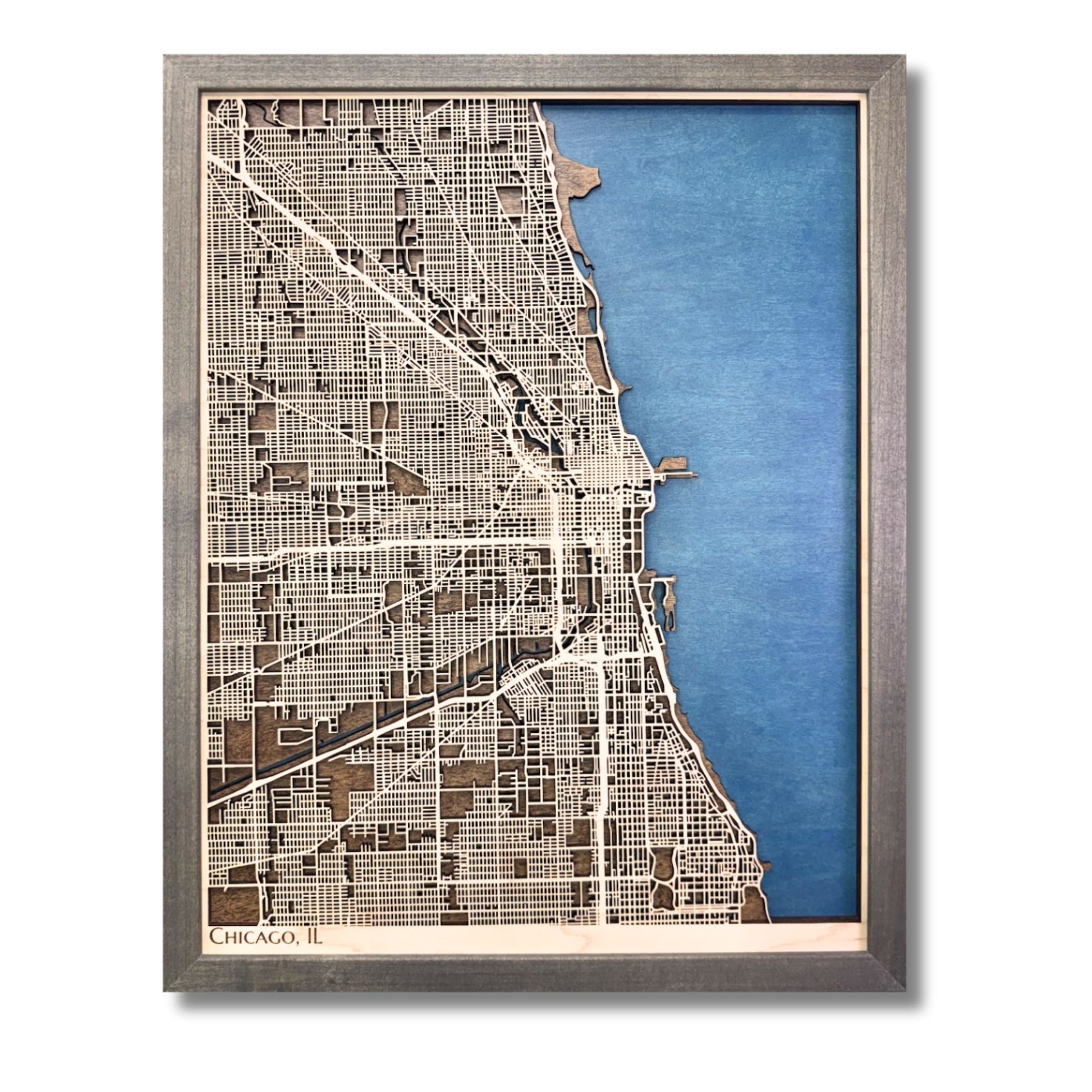 A wooden city map of Chicago with dark blue water stain and beige raised roads.