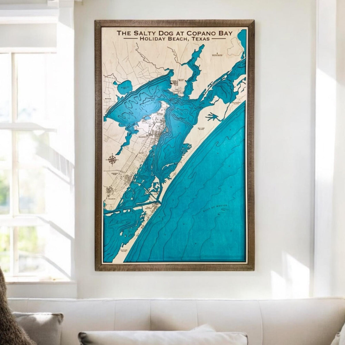 Custom coastal map hanging on a wall in a living room above a couch. 