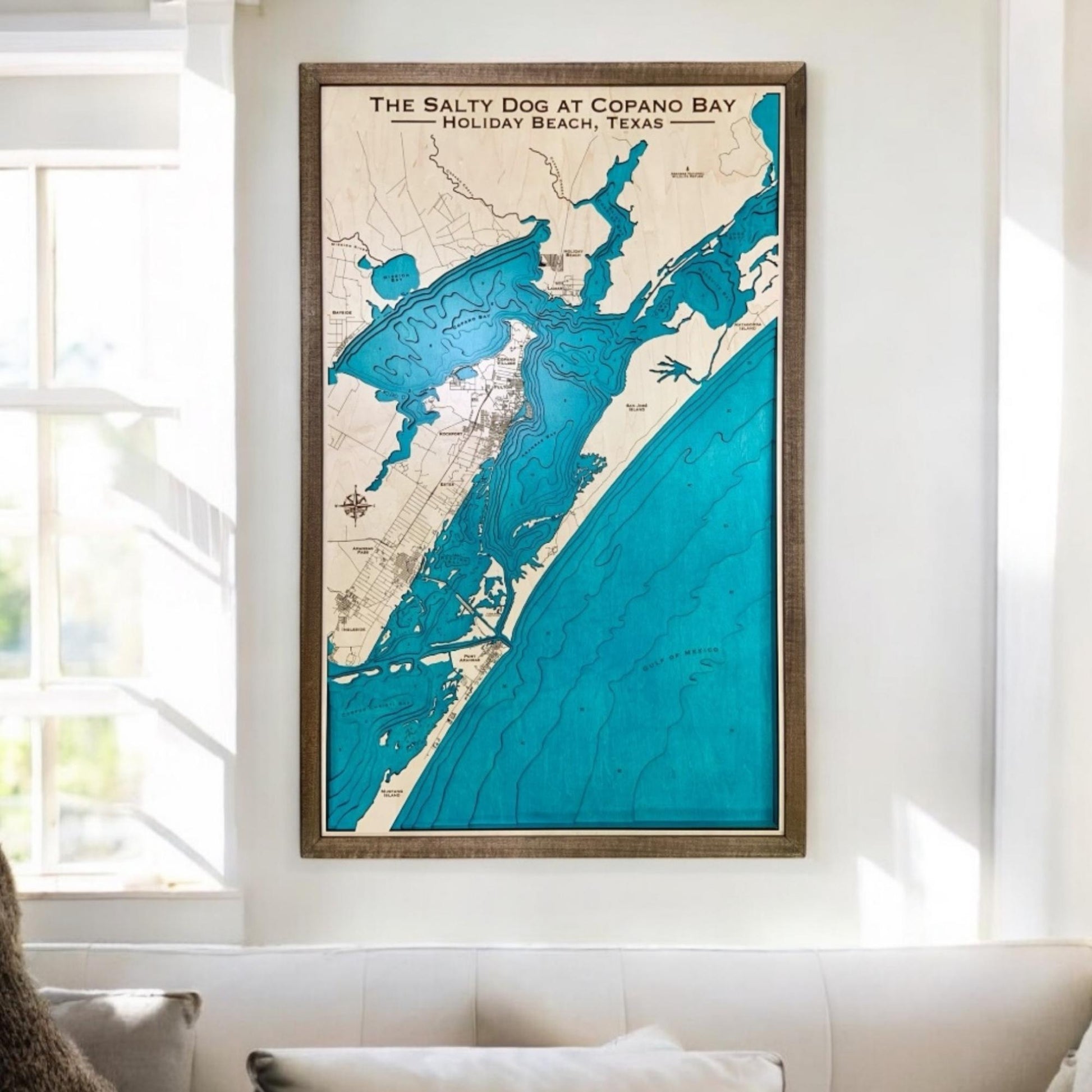 Custom coastal map hanging on a wall in a living room above a couch. 