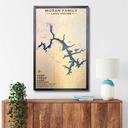 Custom wooden map of Deep Creek Lake on a wall above a wooden cabinet with decor items.