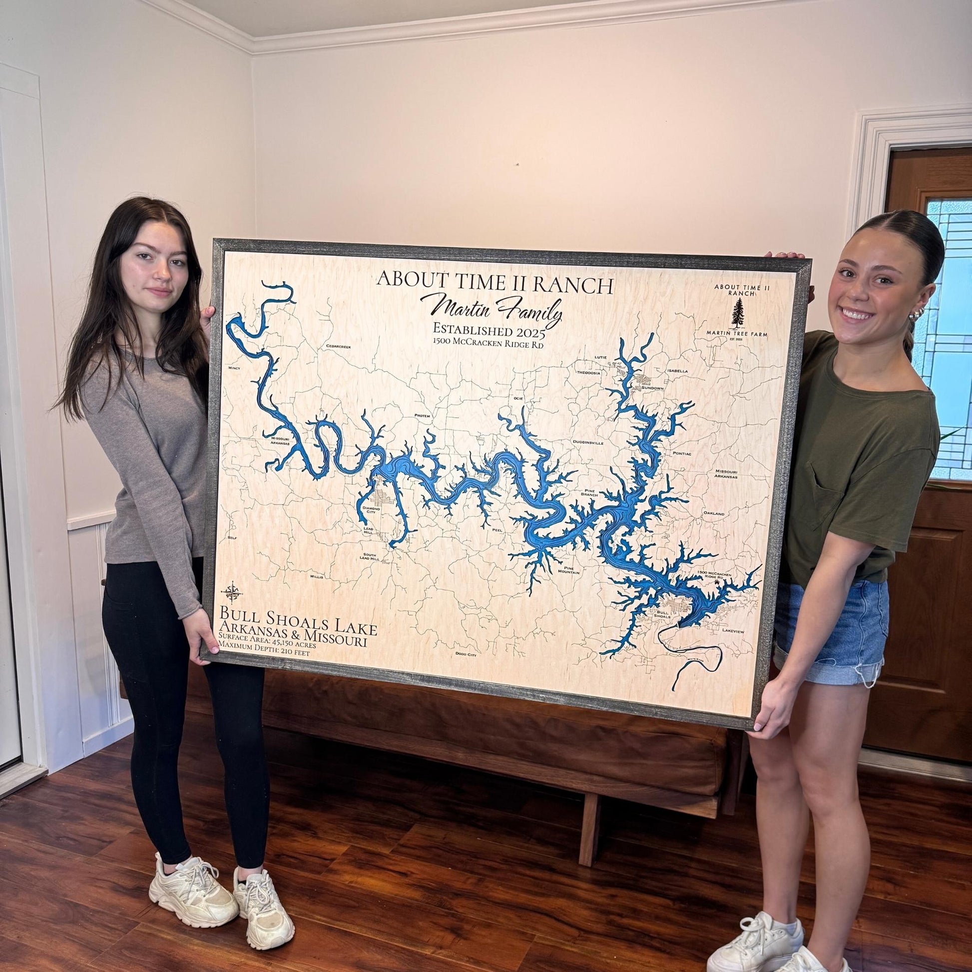 Two women holding a large custom wooden map of Bull Shoals Lake.