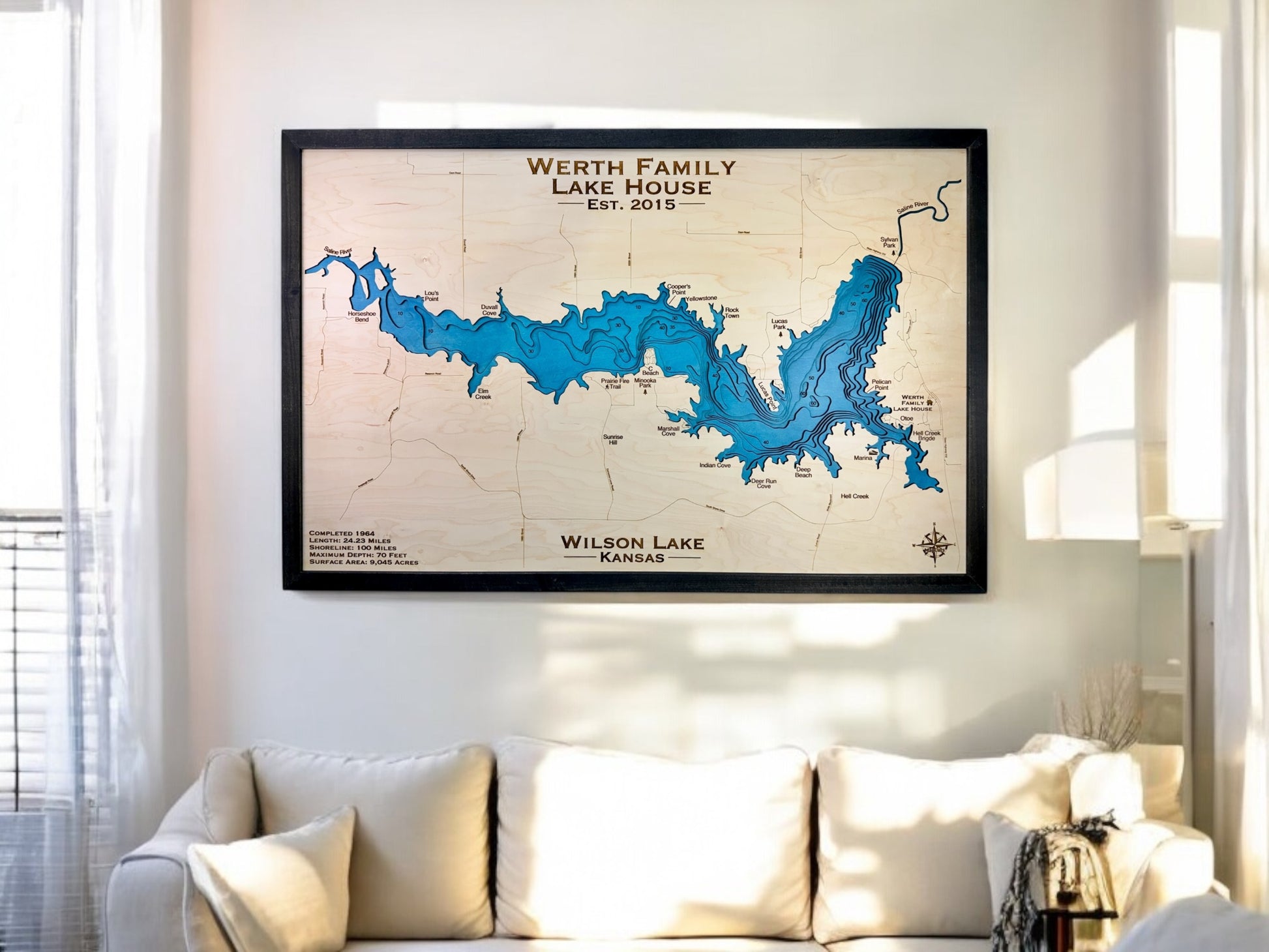 A custom wooden map of Wilson Lake in Kansas hanging on the wall above a couch. 