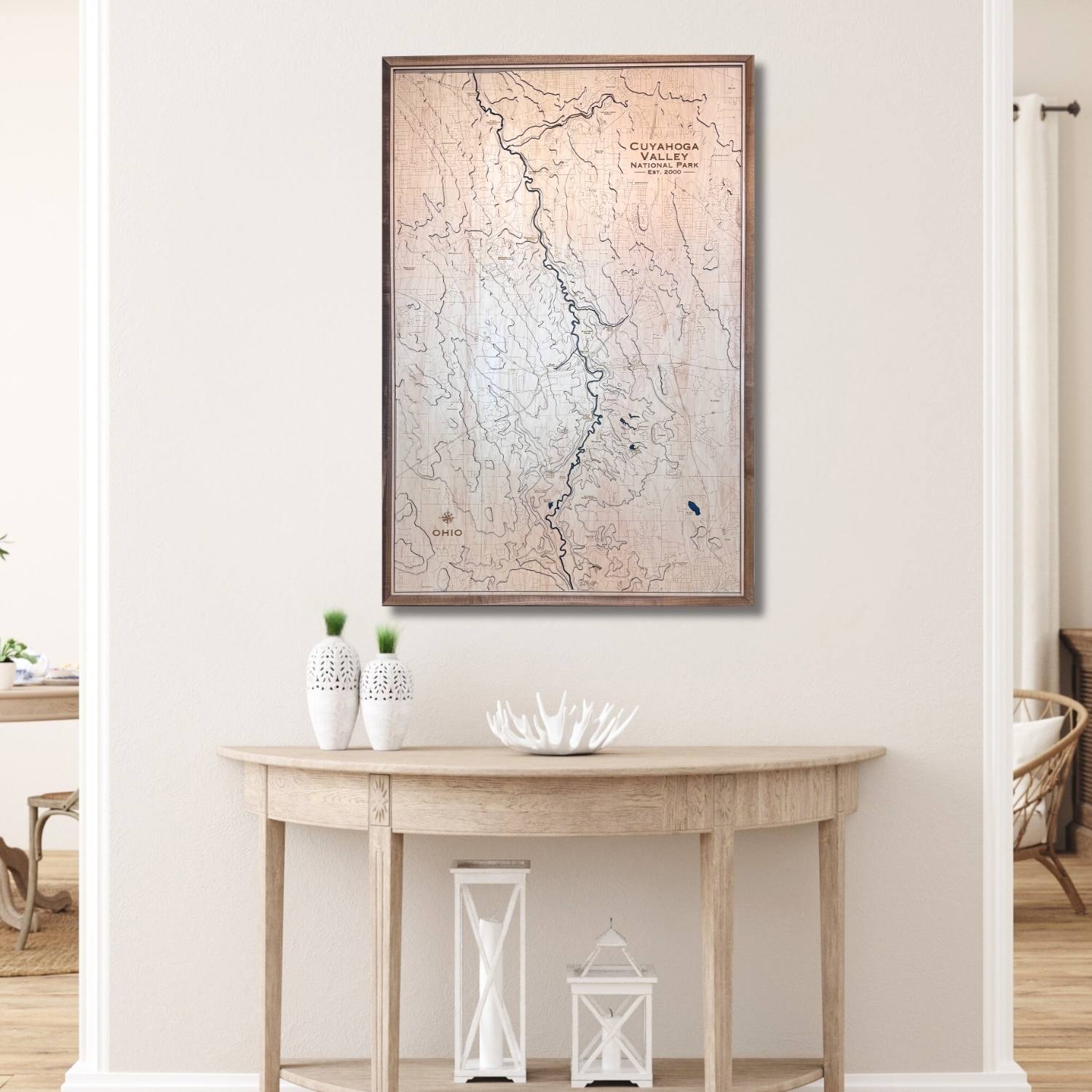 Framed topographic map on a wall above a wooden console table with decorative items.