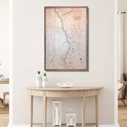 Framed topographic map on a wall above a wooden console table with decorative items.