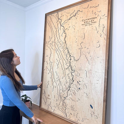 Woman looking at a large topographic wooden map of Cuyahoga Valley National Park on a wall.