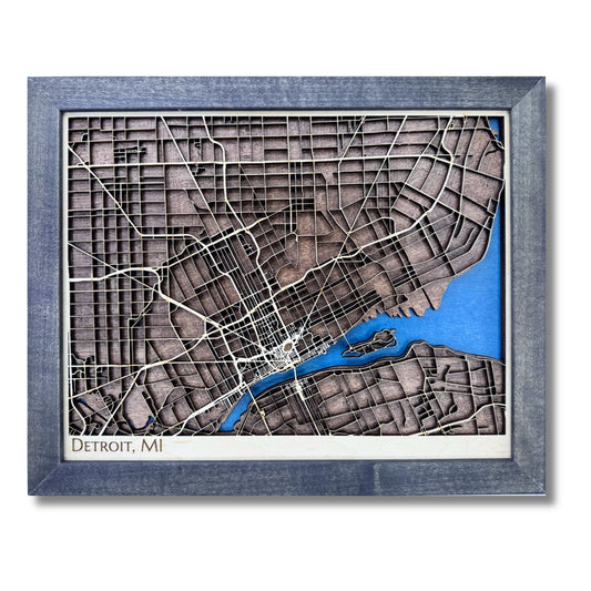 Wooden map of Detroit, Michigan with raised roads, blue water stain, and a black frame. 