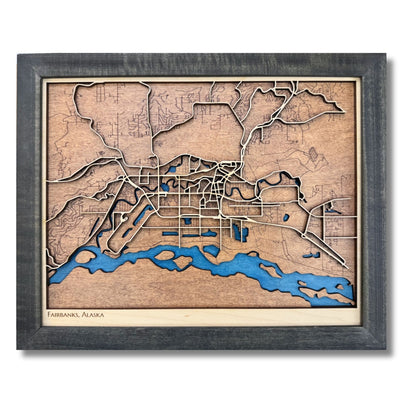 3D wooden map of Fairbanks, Alaska with raised and engraved roads, blue water stain, and a black frame. 