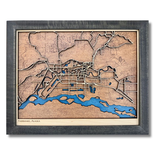 3D wooden map of Fairbanks, Alaska with raised and engraved roads, blue water stain, and a black frame. 