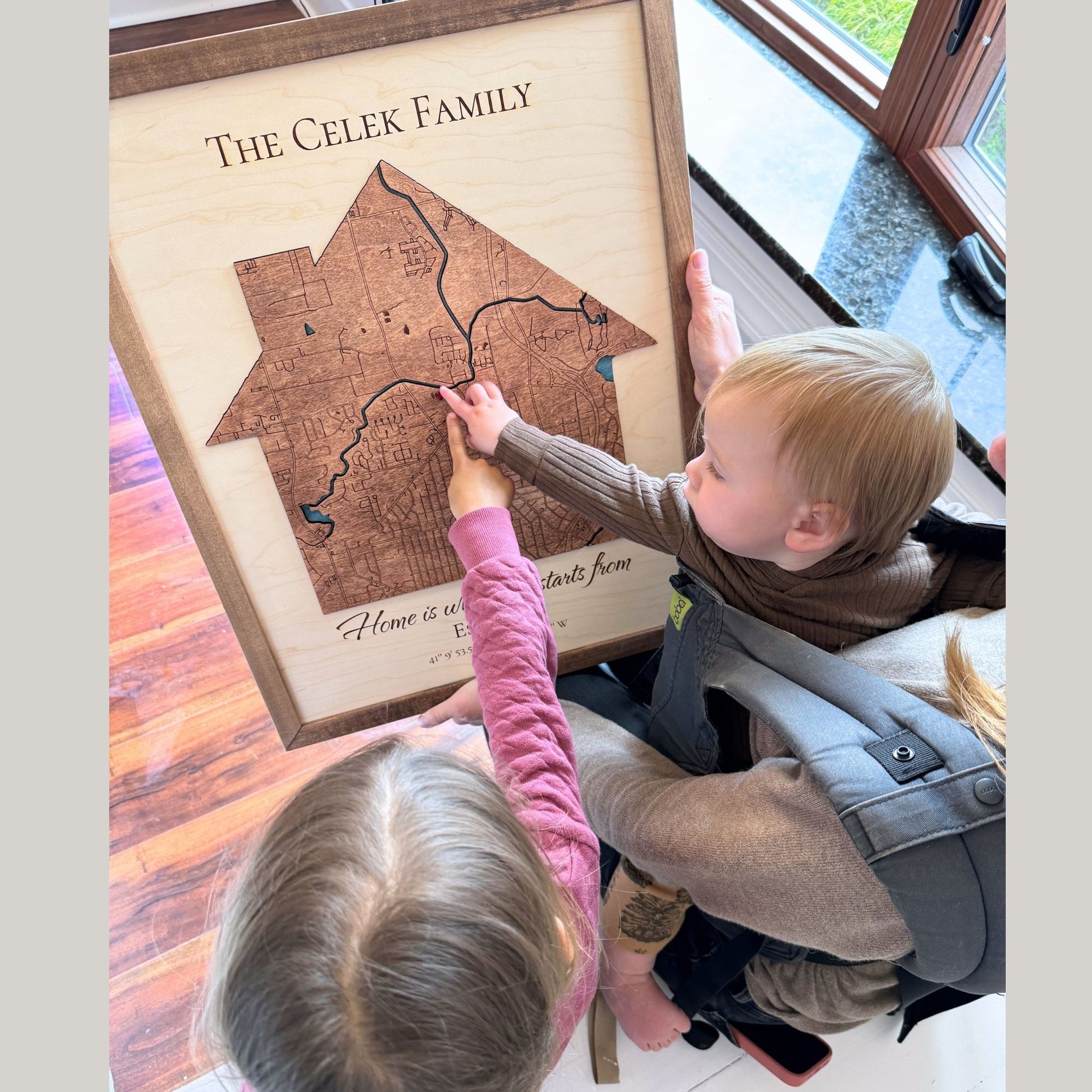 Two children and their mom pointing at the heart icon on a map. 