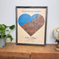 A heart-shaped wood map sits on display on a table.