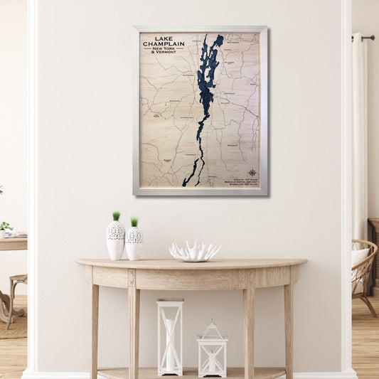 Wooden Lake Champlain map with natural color frame hanging on a wall above a table. 