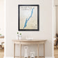 Framed custom map of Lake George with no roads on a wall above a wooden table.