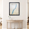 Framed custom map of Lake George with no roads on a wall above a wooden table.