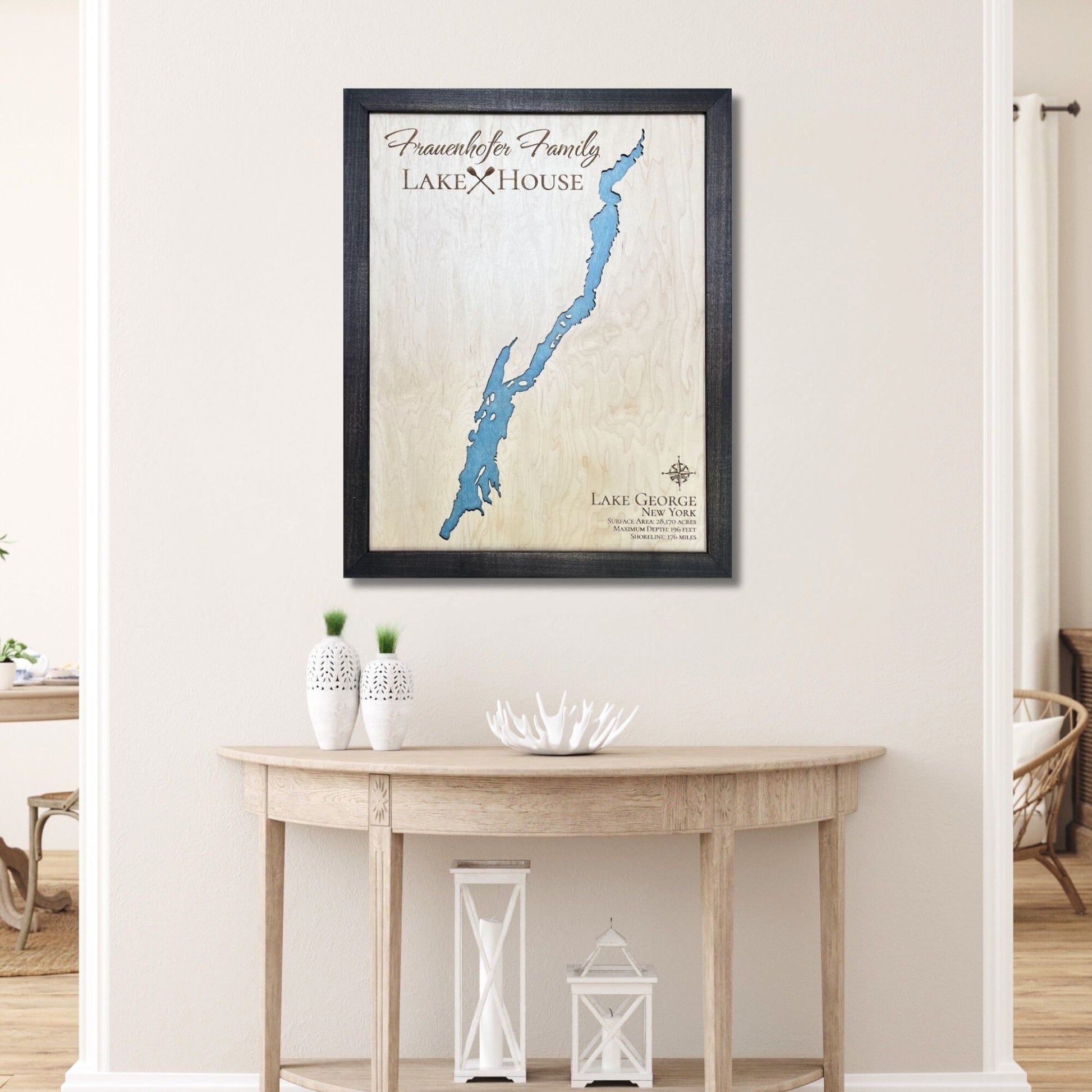 Framed custom map of Lake George with no roads on a wall above a wooden table.