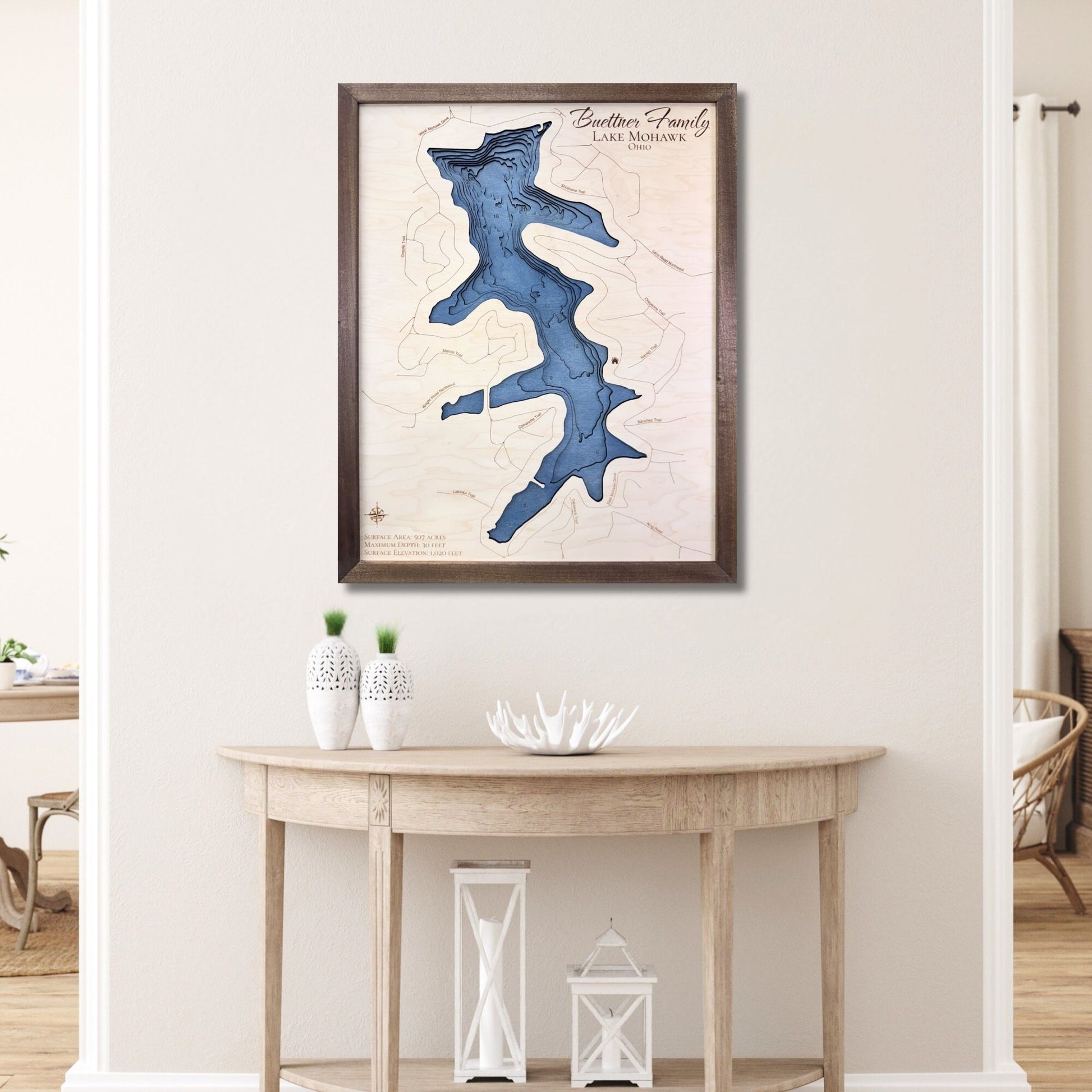 Custom wooden map of Mohawk Lake on a wall above a wooden table in a room.